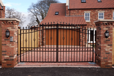 Black metal swinging gates between brick pillars