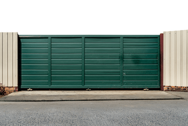 Green sliding gate on a concrete driveway
