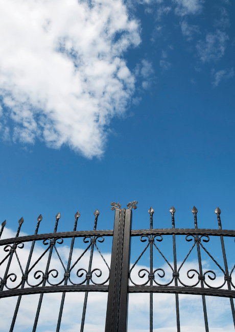 Ornate black metal gate against a blue sky